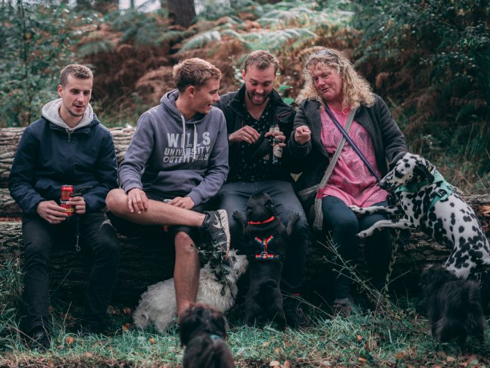 People Sitting on a Log with Dogs