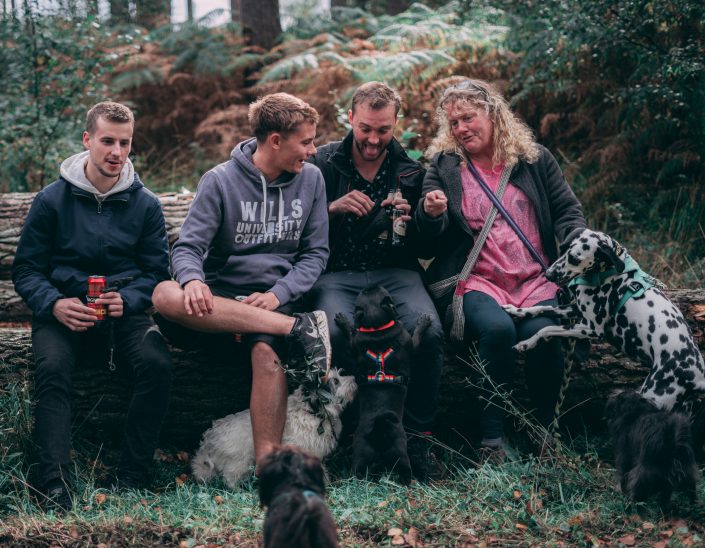 People Sitting on a Log with Dogs